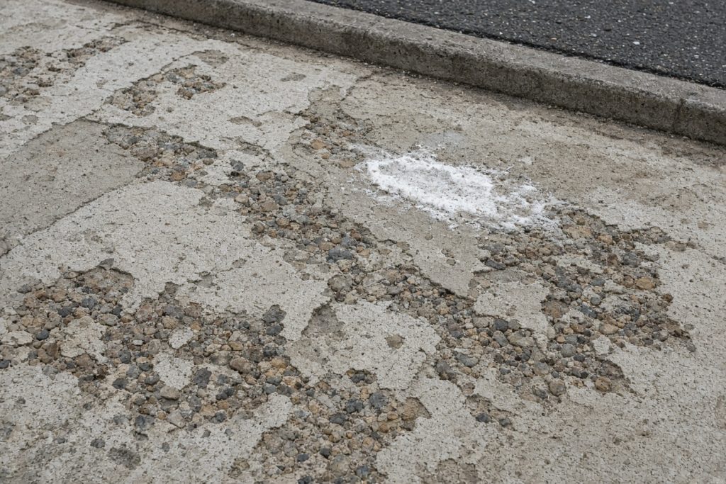 Scaled concrete apron with flaking paste and white salt crust — Concrete Driveways in Lansing