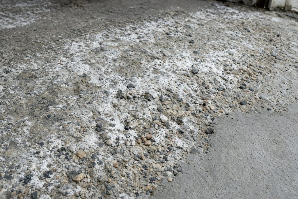 Scaled garage slab with exposed stone and salt film - Concrete Garage Floors in Lowell