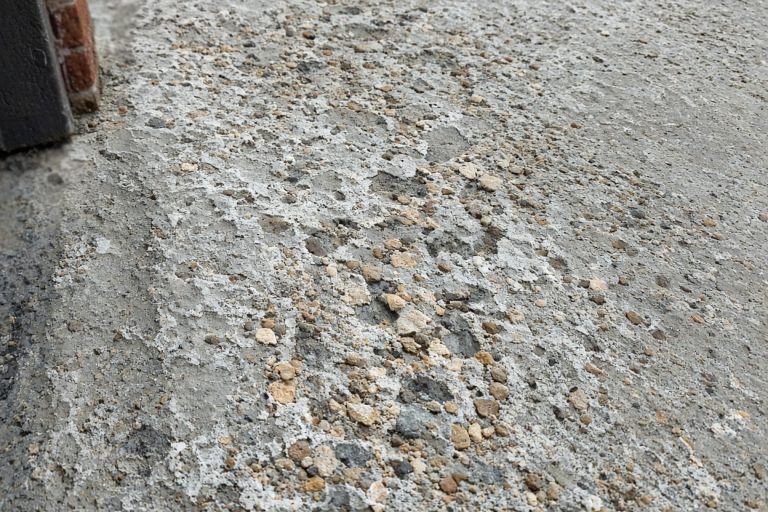 Close view of salt flakes and exposed stone on a driveway — Concrete Overlays in Highland