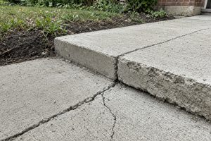 Offset sidewalk joint with one panel raised above the next — Concrete Sidewalks in Griffith