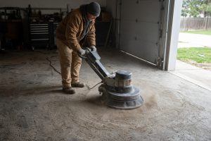 Crew member grinding a garage slab before coating — Epoxy Flooring in South Haven