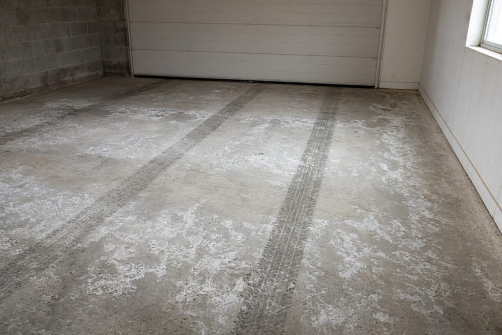 Salt-stained garage slab with two darker tire patches — Garage Floors in Hebron