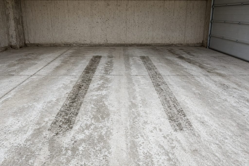 Salt-stained garage slab with two darker tire patches — Garage Floors in Hebron