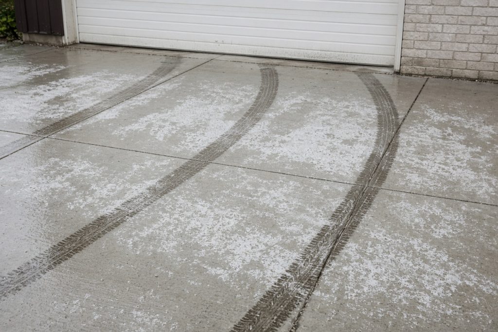 Wet tire tracks and white salt film on a garage slab — Garage Floors in Ogden Dunes
