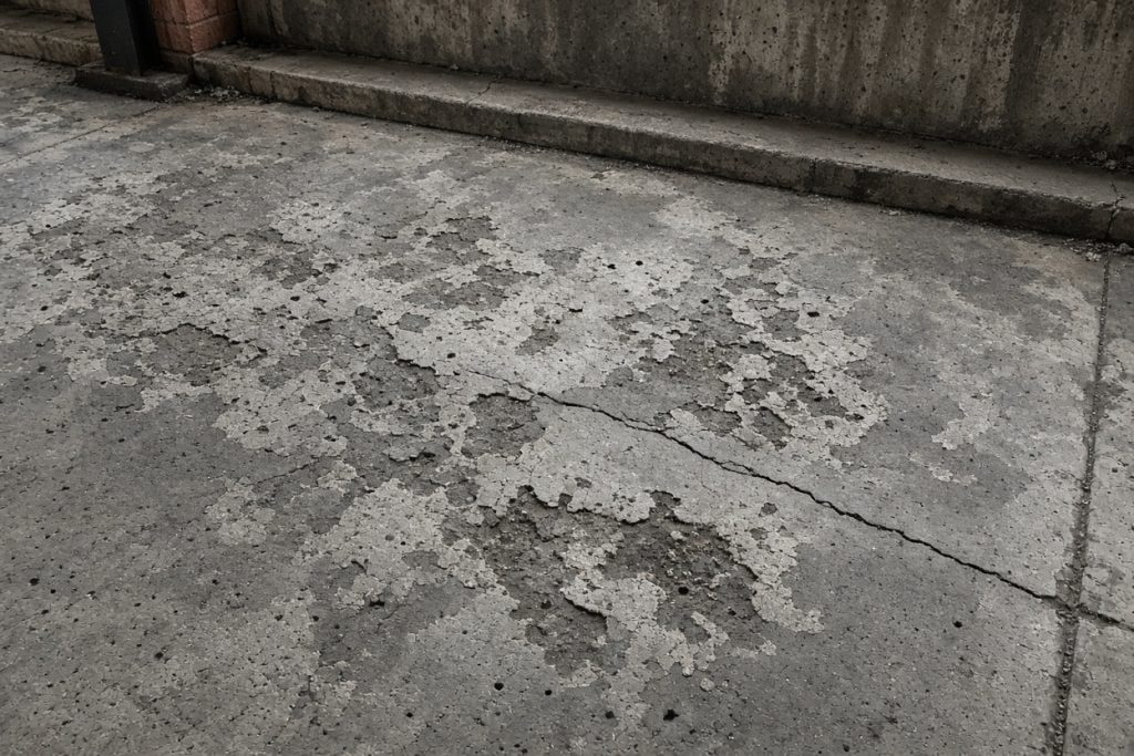 Flaked and pitted concrete in a garage parking stall — Garage Floors in Ogden Dunes