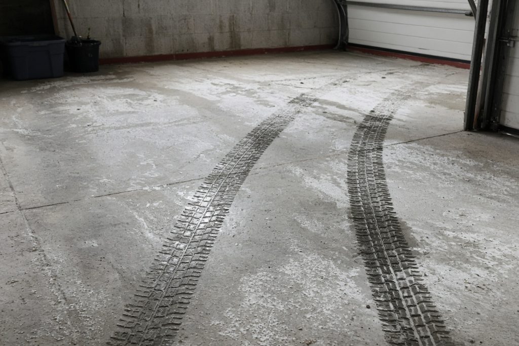 Wet tire tracks and white salt film on a garage slab — Garage Floors in South Haven