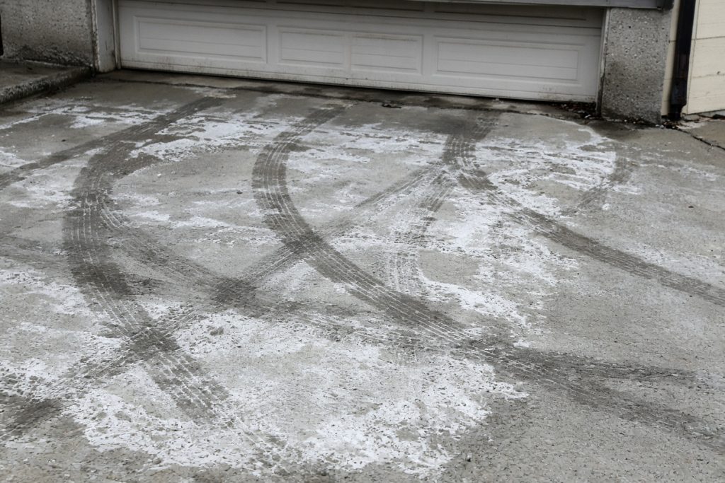 Wet tire tracks and white salt film on a garage slab — Garage Floors in South Haven
