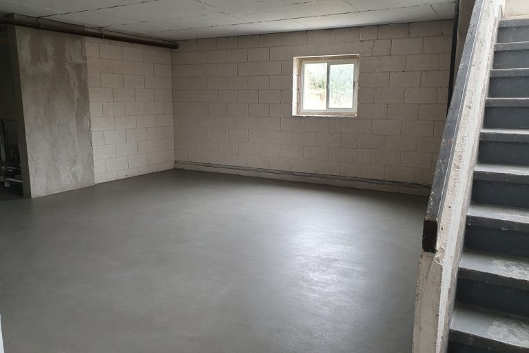Finished basement floor with even gray concrete and a dry wall joint — Concrete Basements in Hebron