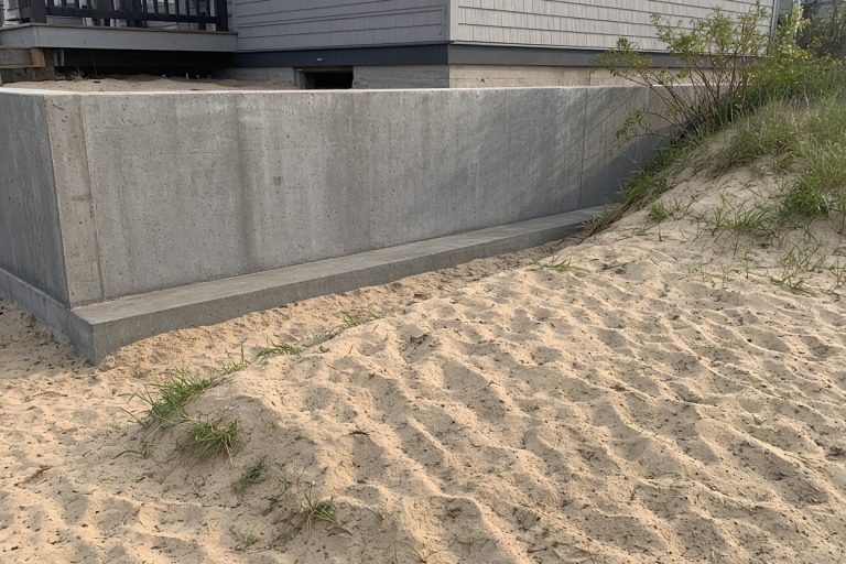 Finished foundation wall and footing beside a dune house — Concrete Foundations in Ogden Dunes