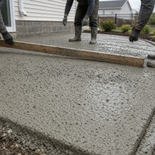 Crew screeding a patio pitched away from a house — Concrete Patios in Portage