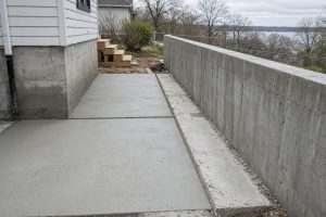Concrete pad and service walk poured next to a yard wall - Retaining Walls in Michigan City
