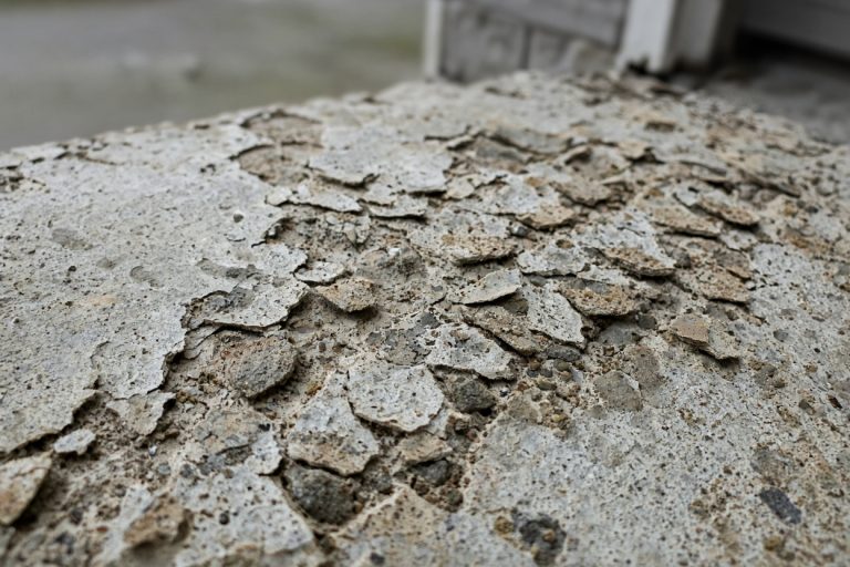 Close-up of scaled driveway paste and exposed stone in a wheel path - Concrete Driveways in South Haven