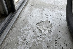 Pitted garage concrete with white dust near the door track — Concrete Garage Floors in South Haven